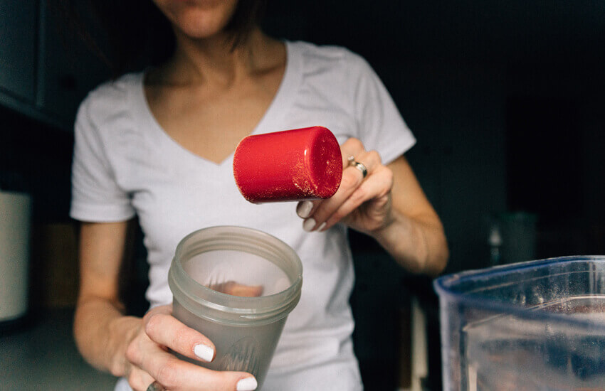 Egy l&aacute;ny feh&eacute;rjeport adagol shakerbe